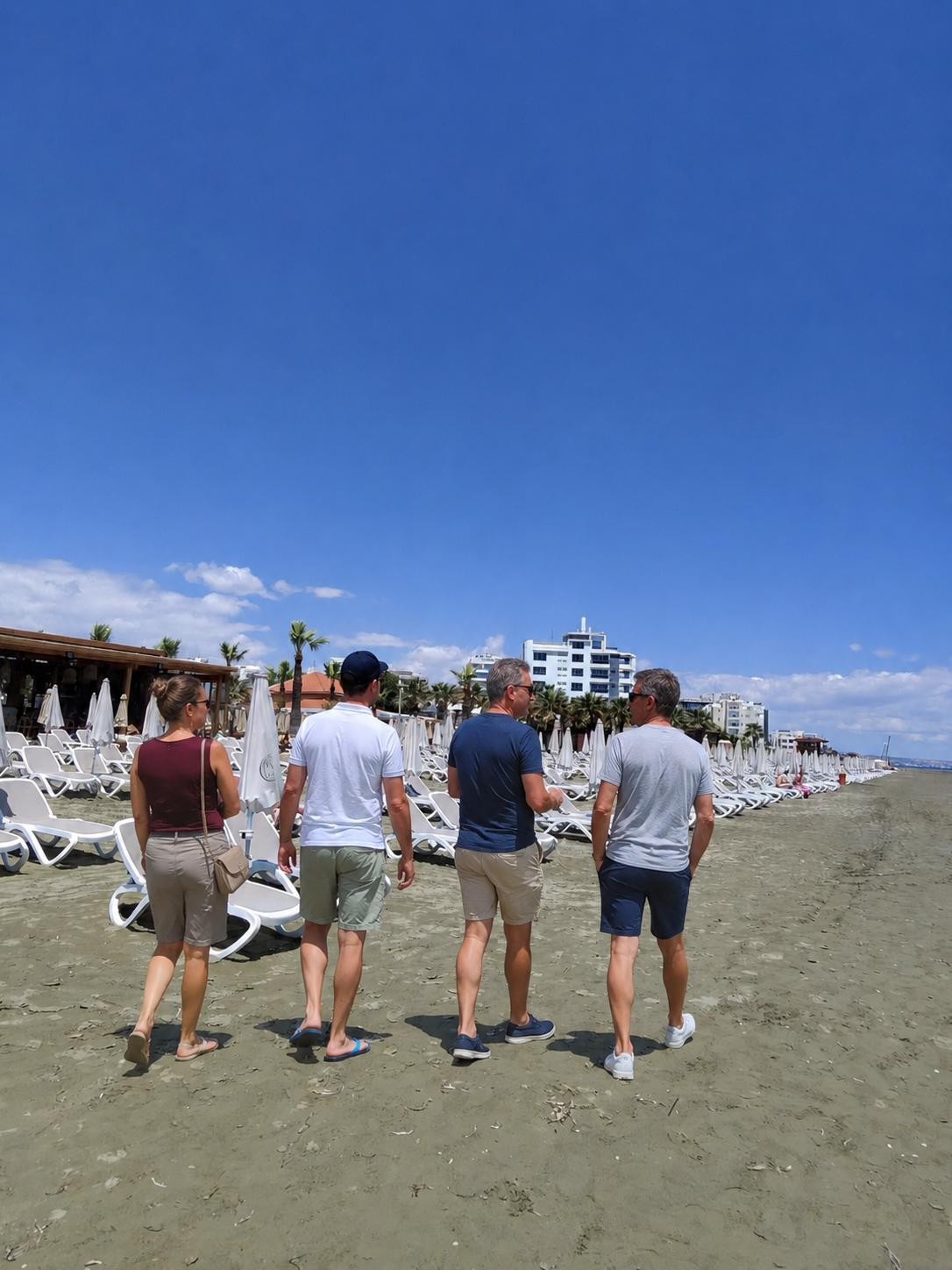 A group chatting as they walk together along a sunny beach in Cyprus