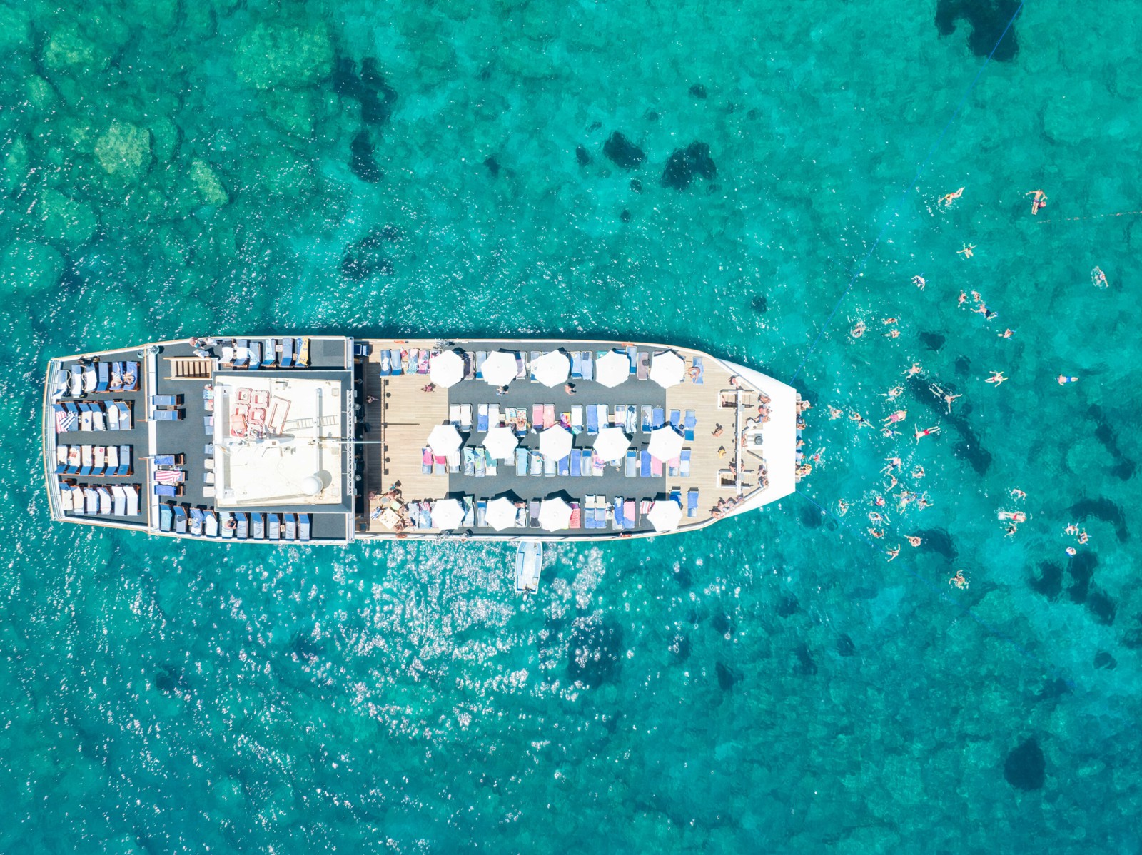 Aerial view of a large Cyprus excursion boat with tables, seating and passengers on turquoise water